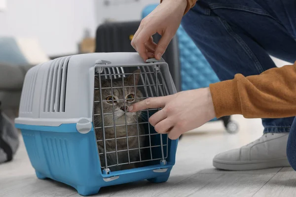 Travel with pet. Man closing carrier with cat indoors, closeup