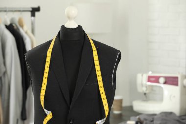 Tamamlanmamış ceketli manken ve terzi dükkanında mezura, yakın plan. Metin için boşluk