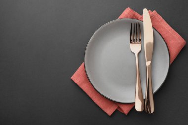 Temiz tabak, çatal bıçak takımı ve peçete gri masada, üst manzara. Metin için boşluk