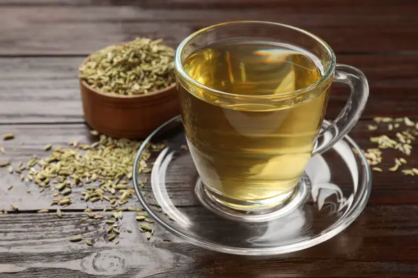 Aromatic fennel tea and seeds on wooden table, closeup. Space for text