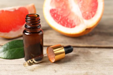 Şişede greyfurt yağı, pipet, yaprak ve meyveler ahşap masada, yakın plan. Metin için boşluk