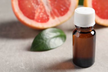 Şişedeki greyfurt yağı gri desenli masada, yakın plan. Metin için boşluk