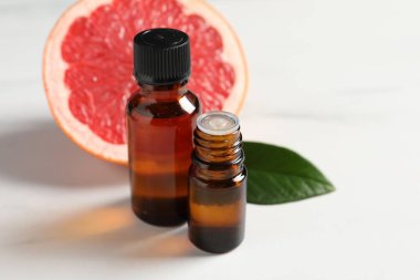 Şişelerde greyfurt yağı, beyaz masada yaprak ve meyve, yakın çekim