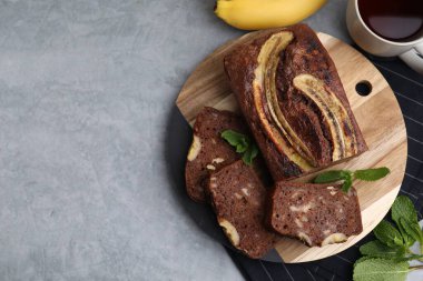 Gri masada servis edilen lezzetli muzlu ekmek, düz. Metin için boşluk