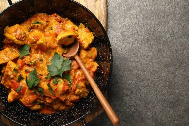 Gri masada tavada ve kaşıkta leziz körili tavuk, üst manzara. Metin için boşluk