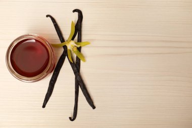 Aromatik vanilya özü, kapsüller ve çiçek beyaz ahşap masa üzerinde, düz yatıyordu. Metin için boşluk