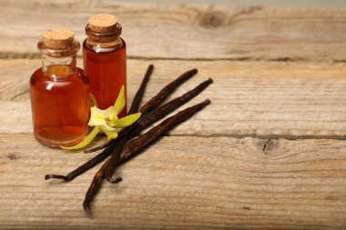 Aromatik vanilya özü, kapsüller ve çiçek ahşap masada. Metin için boşluk