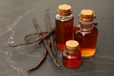 Siyah masanın üzerinde Aromatik vanilya özü ve kapsüller, yakın plan.