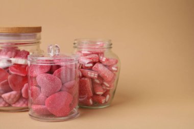 Bej arka planda cam kavanozlarda lezzetli pembe şekerler, metin için yer