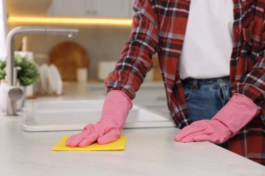 Mutfakta mikrofiber bezle beyaz mermer masayı temizleyen kadın, yakın plan.