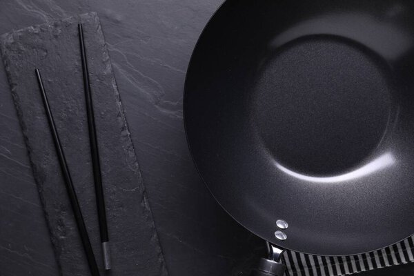 Пустой железный котелок и палочки для еды на черном столе, плоская лежа