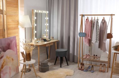 Makyaj odası. Ayna, sandalye ve giysi rafı olan şık bir makyaj masası.
