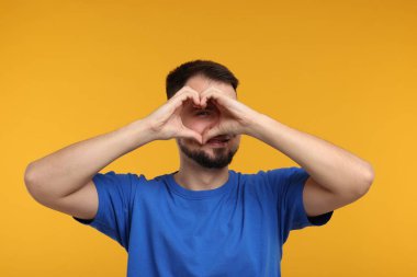 Altın arka planda kalp şeklinde katlanmış bir adam bakıyor.