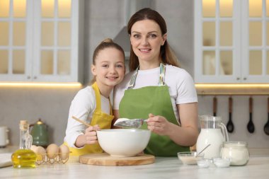 Ekmek yapıyorum. Anne ve kızı mutfaktaki beyaz masada hamur hazırlıyorlar.