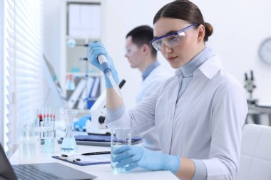 Bilim adamı laboratuardaki deney kabına örnek damlatıyor.