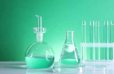 Laboratuvar analizi. Masada yeşil arkaplana karşı farklı cam eşyalar