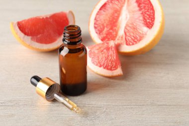 Şişede greyfurt yağı, pipet ve meyveler açık ahşap masada. Metin için boşluk