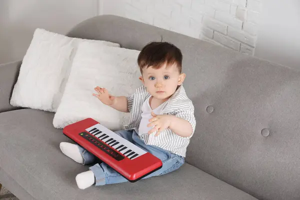 Cute little boy with toy piano at home