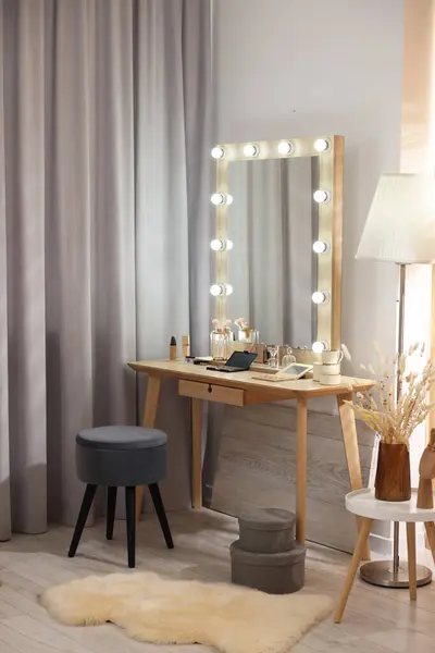 Makeup room. Stylish mirror with light bulbs on dressing table and chair indoors