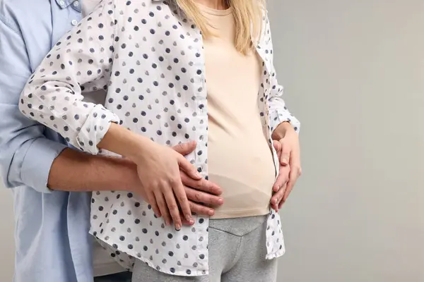 妊娠中の妻の腹を軽い灰色のバックグラウンドで触った男 クローズアップ テキスト用スペース — ストック写真