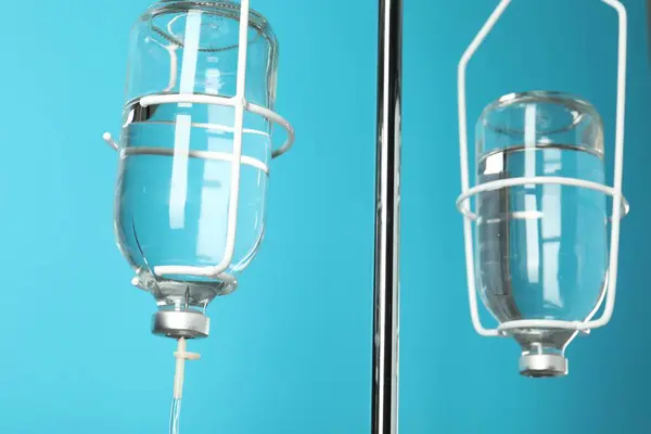 IV infusion set on pole against light blue background, closeup
