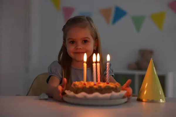 Cute girl with birthday cake at table indoors