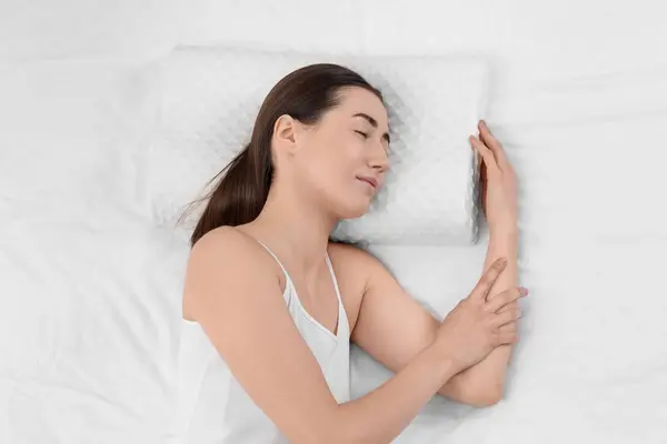 Woman sleeping on orthopedic pillow in bed