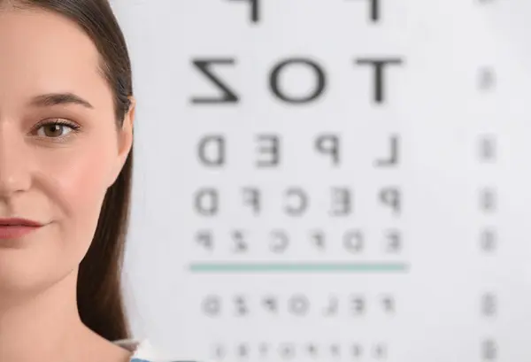 Young woman against vision test chart, closeup