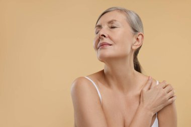 Bej arka planda sağlıklı cildi olan güzel bir kadın, mesaj için yer var.