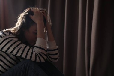 Perdelerin yanındaki üzgün genç kadın, mesaj için yer.