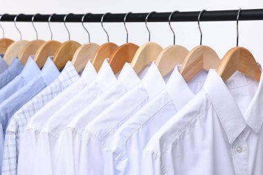 Kuru temizleme servisi. Askıda asılı birçok farklı kıyafet beyaz arka planda, yakın plan