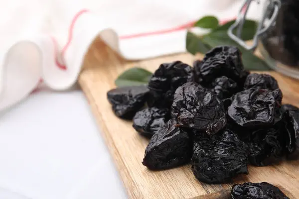 Tasty dried prunes on light table, closeup view