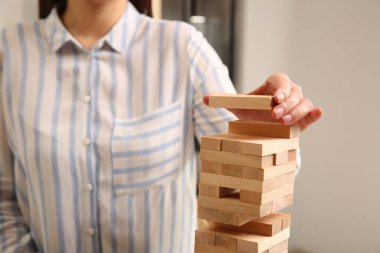 Jenga oynuyorum. Kapalı alanda ahşap blokları olan bir kule inşa eden kadın.