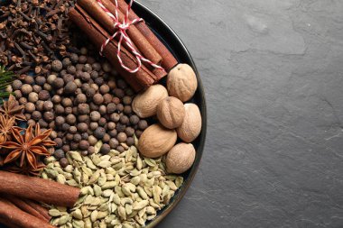 Koyu gri desenli masada farklı baharatlar ve fındıklar, üst manzara. Metin için boşluk