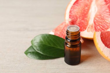 Şişede greyfurt yağı, açık ahşap masada yapraklar ve meyveler, yakın çekim. Metin için boşluk