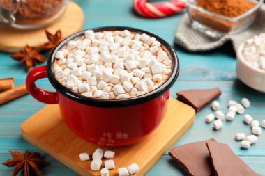 Lezzetli sıcak çikolata, marşmelov ve açık mavi ahşap masa malzemeleri, yakın plan.