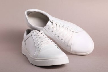 Gri arka planda bir çift şık beyaz spor ayakkabı.