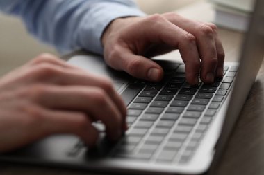 E-öğrenme. Çevrimiçi ders sırasında masadaki bilgisayarı kullanan adam, yakın plan.