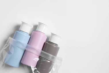 Beyaz arka planda plastik poşet içinde kozmetik seyahat kiti, üst manzara. Metin için boşluk
