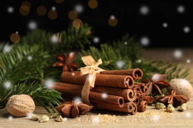 Farklı baharatlar ve ağaç dalları ahşap masada, yakın plan. Tarçın, anason, kakule, hindistan cevizi