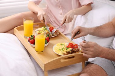 Yatakta lezzetli bir kahvaltı yapan çift, yakın plan.