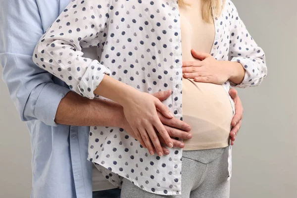ライトグレーの背景に妊娠中の妻の腹に触れる男 クローズアップ — ストック写真