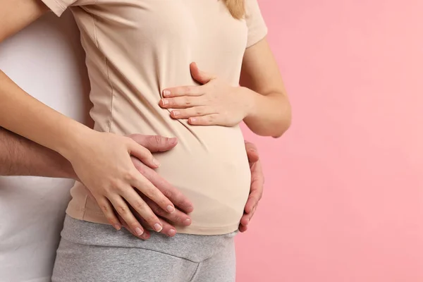 妊娠中の妻の腹をピンクの背景に触れた男 クローズアップ テキスト用スペース — ストック写真
