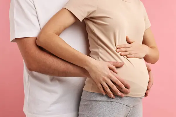 妊娠中の妻の腹にピンクの背景に触れた男 クローズアップ — ストック写真