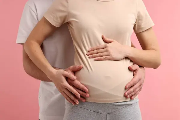 妊娠中の妻の腹にピンクの背景に触れた男 クローズアップ — ストック写真