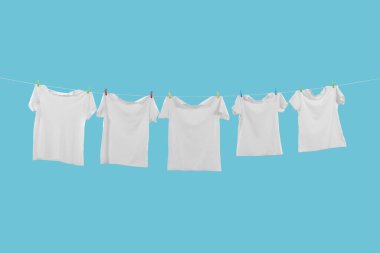 Açık mavi arkaplanda çamaşır ipinde kuruyan tişörtler
