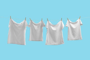 Açık mavi arkaplanda çamaşır ipinde kuruyan tişörtler