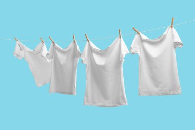 Açık mavi arkaplanda çamaşır ipinde kuruyan tişörtler