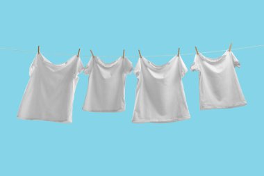 Açık mavi arkaplanda çamaşır ipinde kuruyan tişörtler