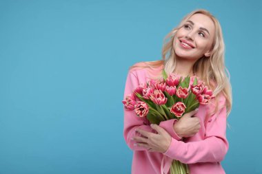 Açık mavi arka planda güzel genç kadın